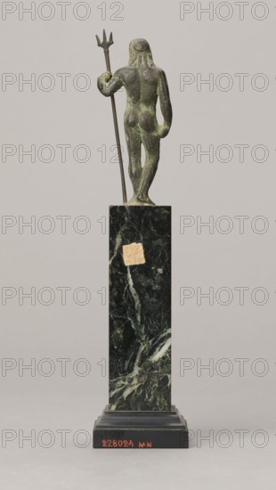 Figurine of Poseidon, unknown Roman workshop. Figurine of Poseidon standing in contrapposto, resting on a trident. The weight of the body rests on the left leg; the right is slightly moved back, the foot bent at the toes. The body is nude, correctly modeled, with clearly defined abdominal muscles. In the left hand the figure holds a trident; the right hand is lowered at the side of the body, holding a cylindrical object at hip level. The head is slightly bowed. The face is framed by long hair and a beard. 1st century, Roman Empire 27 BC–476. Bronze figurine; height 8.7 cm, width 3.5 cm, depth 1.8 cm, weight 0.362 kg with base., A small bronze figurine with a greenish patina stands on a tall dark green marble plinth; the figure is shown from the back holding a long thin trident in one hand, with a rounded head and stylized hair, and a weathered surface; the plinth has lighter veining and a small patch of lighter material, and rests on a stepped black base; the background is a pale neutr...