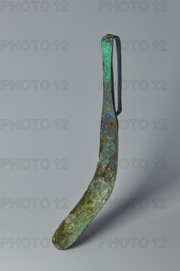 Scraper, Metal scraper with a typical slightly curved shape consisting of a handle and a blade with a slightly rounded end. 6th–4th century BC, possibly Rome; tool. Height 4.5 cm, width 28 cm, depth 11 cm, weight 0.11 kg., An elongated curved metal object with a looped handle, showing a textured surface with patina in shades of green, blue, brown, and hints of dark gray, suspended against a plain pale gray background; the metal shows areas of rough corrosion, mottled discoloration, and varied surface sheen.