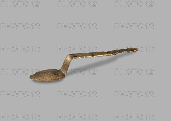 Medical tool fragment of strigil?, possibly by Antoni Madeyski 1862–1939, tool, height 12.8 cm, A metallic spoon-like object with a rough, uneven surface and an irregular bent handle lies on a plain background; the object appears in shades of gold and brown with darker tarnished spots, and the background is a uniform gray.