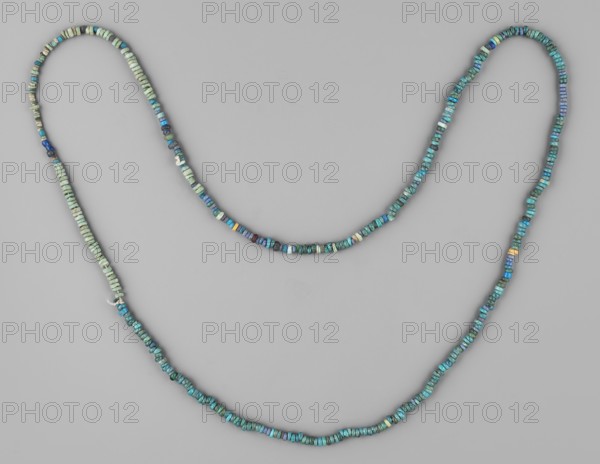 Necklace, necklaces, ornaments, disc-shaped beads, object made of small disc-shaped beads, ca. 1550–1295 BC; New Kingdom, 18th Dynasty, Egypt, jewelry, height 35 cm, A long beaded strand arranged in a loose double-curve against a plain light gray background, composed of a few types of small disc-shaped beads in shades of turquoise, teal, blue, green, and a few pale beige and dark blue beads, with beads varying slightly in size and irregular shape and a small visible knot where the strand overlaps.