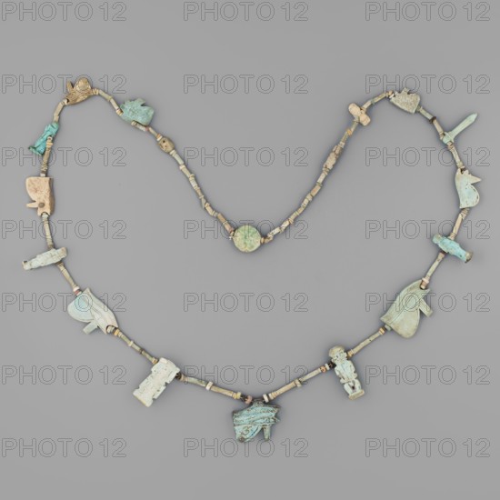Necklace with amulets, udjat eyes, tit knots, Ptah the dwarf, Toeris, necklaces, columns, auletes separated by tubular and disc-shaped beads: 8 udjat eyes, Isis knot, Toeris, papyrus column, Ptah the dwarf, 2 anthropomorphic deities, 2 plaques; ca. 1550–332 BC, New Kingdom–Late Period, Egypt, amulet, height 70 cm, A beaded necklace arranged on a gray background showing a string of small cylindrical and disc-shaped beads in beige, tan, and light brown, interspersed with a few larger carved pendants in shades of pale blue, turquoise, greenish-blue, cream, and light beige; the pendants include a few stylized animal and figure shapes and some abstract carved forms, each pendant displaying weathered surfaces and subtle color variations; the overall palette includes gray from the background and the beads’ beige and tan tones alongside the blue and green hues of the larger pieces.