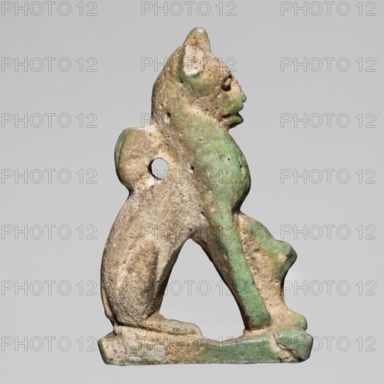 Amulet — cat; creator, material: amulet; subject: cat; function: pendant; date: ca. 945–525 BC 22nd–26th Dynasty, Egypt; dimensions: height 3.3 cm, width 2 cm., A sculpted small figure of an animal in profile, carved with rounded contours and a hole through its body, showing a head with defined ears and a snout, front and hind legs with paws resting on a narrow base; the surface shows a weathered texture with areas of green and beige, along with some darker and lighter tonal variations.