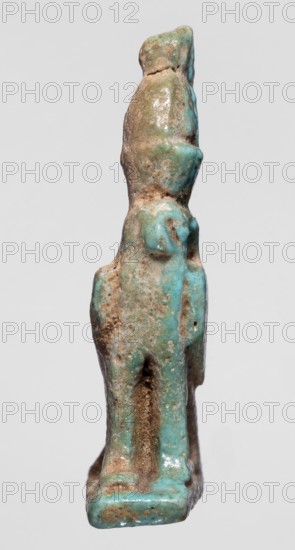 Amulet of Horus in the form of a falcon sitting on a rectangular base with a double crown on its head; Late Period, 664–332 BC, Egypt; material: amulet; subject: falcons, sacred animals; height 4.9 cm, width 2.5 cm., A small vertical figurine with a rough, weathered surface showing a mix of turquoise, green, brown, and beige tones, standing on a rectangular base of similar colors; the form appears elongated with rounded protrusions and indentations, a narrowed midsection, and a slightly bulbous top; the surface has glossy areas and mottled patches of earthy deposits, with some textured pits and streaks of darker brown.