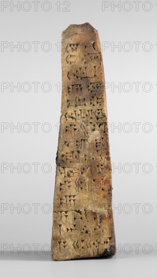 Votive obelisk with an inscription of King Ashurbanipal forgery with a copy of an ancient text, cuneiform writing, Ashurbanipal king of Assyria; ca. 668–ca. 631 BC, votive offerings, obelisks, inscriptions, forgeries. Clay votive obelisk of King Ashurbanipal. The obelisk tapers towards the top. Cuneiform text inscribed on all four faces of the object. c. 668–c. 631 BC; Neo-Assyrian period dating the content of the copied inscriptions from the reign of Ashurbanipal, 2nd half 19th century–1st half 20th century forgery. Iraq inscription on which the copied text is based, Quyunjik inscription on which the copied text is based, Nineveh inscription on which the copied text is based, unknown place of creation forgery; probably from the Middle East. Document; dedication. Height 13.1 cm; width 3.7 cm; thickness 4.2 cm., A tall, narrow, wedge-shaped object standing upright with an irregular top and a flat base, showing a weathered, rough surface with carved indentations and shallow grooves acros...