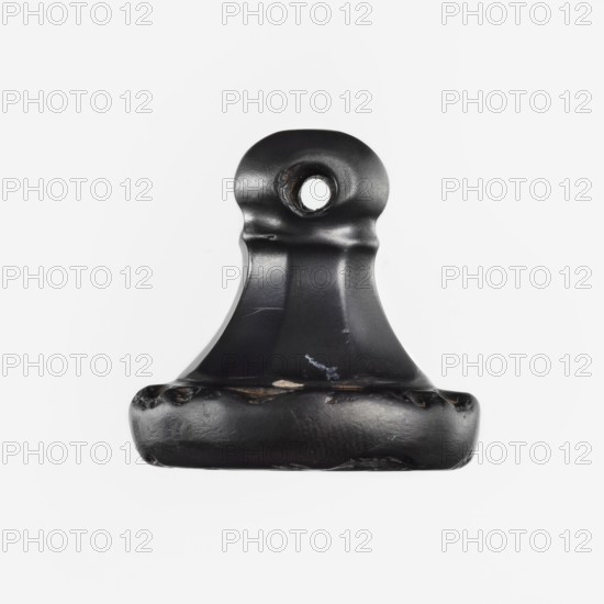 Stamp seal, unknown ancient Hittite workshop. Hittite stamp seal made of hematite. Carefully crafted handle with eight surfaces that taper upward, terminating in a ring and a spherical grip with a horizontally drilled hole. Circular base bears two circles of ornament: a larger spiral-tendril outer ring and a smaller inner braid. Two characters imitating Hittite hieroglyphic writing were added to the smaller circle in the 19th century. Date: 17th–14th century BC; Old Hittite period Hittite hieroglyphic characters added in the 19th century. Place of origin: Karahöyük Adiyaman Province, Turkey, Hittite Empire c.1650–c.1178 BC. Material: hematite. Object type: seal. Dimensions: height 3.1 cm, width 3.3 cm., A single black metal clip with a rounded top and a hole near the top, showing worn and chipped edges and some scuffed areas, photographed against a plain white background; visible colors include black, white, and small hints of brown where the finish is worn.
