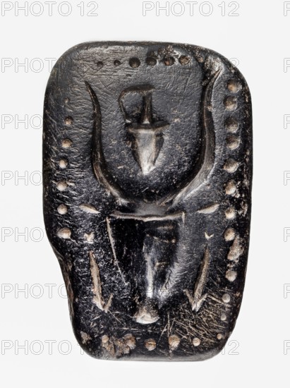 Stamp seal with a depiction of a bull's head. Stamp seal with a full, arched handle with a horizontally drilled hole. On its rectangular base is carved a schematic bull's head with small ears and long, curved horns, between which is a jug with a triangular belly and a long, narrow neck with a handle. On either side of the bull's muzzle are carved short arrows with triangular heads pointing downwards—possibly a simplified representation of snakes. The whole is framed with beadwork. Unknown Cypriot workshop. Late Bronze Period, 14th–13th century BC previously c. 1450–1250 BC. Cyprus. Seal. Height 3.2 cm; width 5.4 cm; depth 3.5 cm., A small, dark object with a rounded rectangular shape and a worn, slightly glossy surface showing lighter worn areas; the top features a carved, central raised motif resembling a curved U-shape with a vertical element inside, and there are a few small circular indentations forming a border along the top and sides; the lower portion shows carved angular lines ...