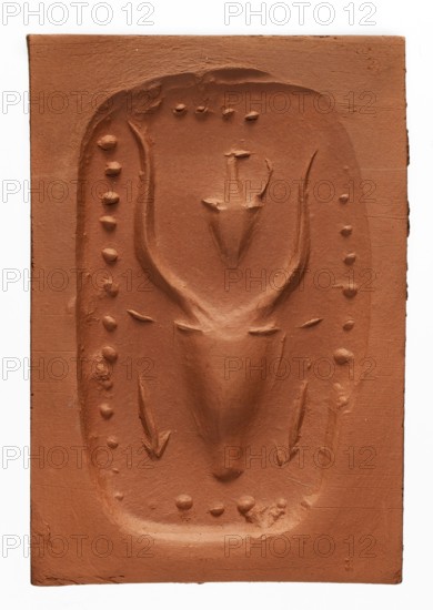 Stamp seal with a depiction of a bull's head, unknown Cypriot workshop. Stamp seal with a full, arched handle with a horizontally drilled hole. On its rectangular base is carved a schematic bull's head with small ears and long, curved horns, between which is a jug with a triangular belly and a long, narrow neck with a handle. On either side of the bull's muzzle are carved short arrows with triangular heads pointing downwards—possibly a simplified representation of snakes. The whole is framed with beadwork. 14th–13th century BC; Late Bronze Period. Cyprus. Seal; height 3.2 cm, width 5.4 cm, depth 3.5 cm., A rectangular terracotta-colored clay plaque with a recessed central panel containing a raised relief of an abstract animal head with curved antler-like shapes, a tapered snout, and a few raised rounded bumps around the inner border, all rendered in the same reddish-brown color with visible tool marks and slight surface texture variations.