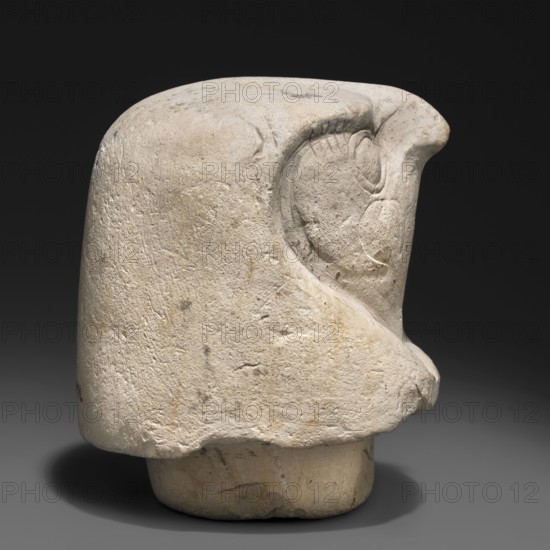 Canopic jar lid - falcon head, unknown creator; canopic jar; Sons of Horus mythology; falcon iconography; Egyptian art; Egyptian sculpture; Kebehsenuf mythology. Canopic jar lid in the shape of a plastically modeled falcon head, with details around the beak and eyes rendered with delicate modeling. On the underside, a wide tenon securing the lid in the urn's opening. 664–332 BC, Late Period, Egypt. Canopic jar; height 11 cm, width 9 cm., A roughly carved stone object with a rounded top and a bulbous protrusion on one side, showing a carved recessed curve resembling an eye area and layered contours. The surface is textured and pitted, with visible tooling marks and small chips, and the stone displays shades of off-white, beige, pale gray, and hints of warm tan. The object sits against a dark background casting a soft shadow, and its base appears slightly narrower with an irregular bottom edge.