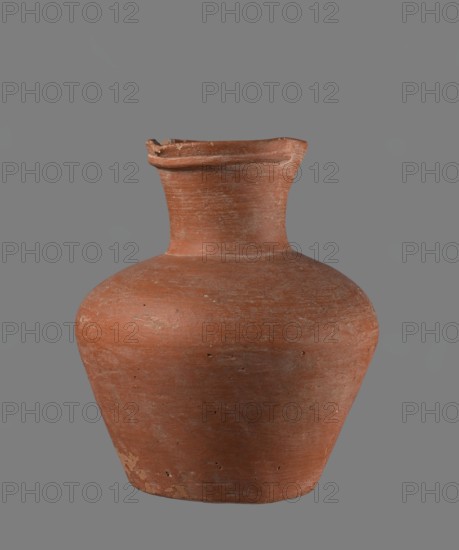 Jug. Jug with a biconical belly, widest at about half its height; broad, not very sloping shoulders; wide neck slightly widening toward the spout, the neck about one-third of the vessel's total height. Spout profiled, irregular, slightly raised and extended on one side forming a small secondary spout; cross-section almost triangular with a ~1 mm indentation at centre of outer profile. Bottom very slightly rounded. Made of Nile clay NB1? according to the Vienna System. Neck was made separately and joined to the body; joint traces erased. Outer surface smoothed, covered with an engobe and polished. Inner surface smoothed except for the neck, which is also engobed and polished. Color reddish-brown. Well preserved with slight chipping at the rim and areas of engobe worn off on the outer surface. Edfu — local workshop. Old Kingdom comparative parallels: Reisner, type XIX–XX, ca. 2686–2181 BC. Measurements referenced in comparative material: example height 17.4 cm; rim Ø 8.1 cm; body Ø 15 cm...