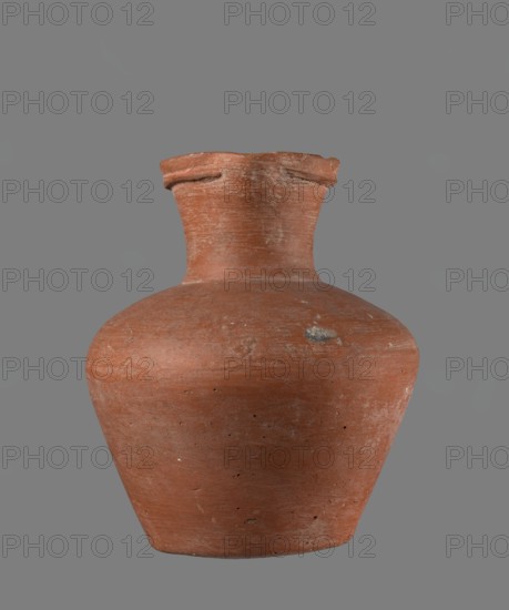 Jug with biconical belly. Vessel is widest at about half its height; broad, not very sloping shoulders; wide neck slightly widening toward the spout, the neck about one-third of total height. Spout profiled, irregular, slightly raised and extended on one side forming a small secondary spout; almost triangular in cross-section with a c. 1 mm indentation in the centre of the outer profile. Bottom very slightly rounded. Made of Nile clay NB1 per Vienna System. Neck was made separately and joined to the body; joint traces erased. Outer surface smoothed, covered with engobe and polished; inner surface smoothed except for the neck, which was also engobed and polished. Reddish-brown color. Fairly well preserved; rim slightly chipped in two places and engobe worn off in places on the outer surface. Local workshop at Edfu. Comparative typology: Reisner, type XIX–XX, Old Kingdom ca. 2686–2181 BC; comparable vessel with height 17.4 cm, rim Ø 8.1 cm, body Ø 15 cm, base Ø 8.6 cm., A single terracot...