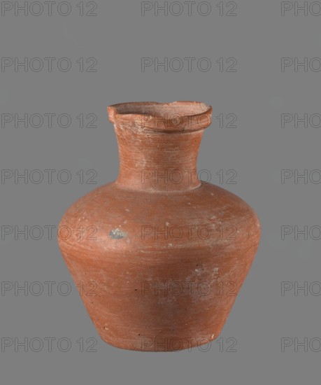 Jug. Jug with a biconical belly, widest at about half its height. Broad, not very sloping shoulders. Wide neck, slightly widening toward the spout; neck height about one-third of total vessel height. Profiled, irregular spout, slightly raised and extended on one side forming a small secondary spout; spout nearly triangular in cross-section with an approx. 1 mm indentation at center of outer profile. Bottom very slightly rounded. Made of Nile clay NB1? per Vienna System. Neck was made separately and joined to the body; joint traces erased. Outer surface smoothed, covered with an engobe and polished. Inner surface smoothed except for the neck, which was also covered with engobe and polished. Color reddish-brown. Well preserved; rim slightly chipped in two places and engobe worn in places on outer surface. Provenance: Edfu — local workshop. Comparative material: Reisner, Mycerinus, fig. 69 1–2, types XIX–XX, ca. 2686–2181 BC Old Kingdom; comparable vessel: height 17.4 cm, rim Ø 8.1 cm, bo...