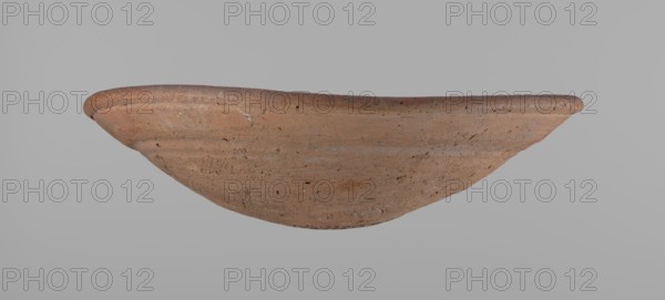 Bowl. Shallow bowl of rounded, asymmetrical shape with a rounded, flaring, irregular rim. Surface is level. Lower half of the bowl was finished with a knife or similar tool. Slightly above mid-height, a horizontal line—likely from placement on a stand—is visible. Color: dark red. Vessel complete. Made in a local Edfu workshop. Old Kingdom, ca. 2686–2181 BC. Height 7.2 cm; rim diameter 26.2 cm., A shallow, curved clay bowl with a rough, textured surface is shown against a plain gray background; the bowl is predominantly reddish-brown with variations of tan and darker brown speckles, and it has a slightly raised, rounded rim and visible marks and small pits across its exterior.
