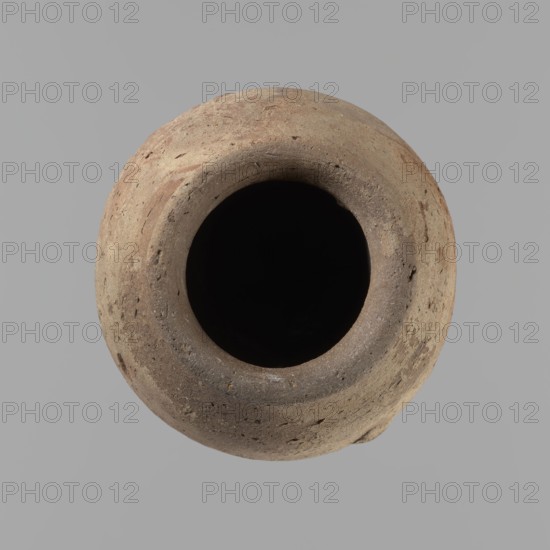 Vessel with hieratic inscription. Conical Nile-clay NB2 vessel, tapering toward a pointed bottom; irregular, widest at approx. 3/4 of the height. Narrow, slightly sloping shoulders; short, wide neck; very gently rounded, slightly flaring rim. Handcrafted, with upper part shoulders, neck, rim turned. Smooth surface, externally probably covered with engobe. Remains of a hieratic inscription in black on the lower belly. Complete, well preserved. Old Kingdom, ca. 2686–ca. 2181 BC; findspot Edfu. Height 12.9 cm; rim diam. 5.5 cm; body diam. 7.8 cm. Comparative parallels: Petrie Dendera, Abydos, Hope Akhmim, Reisner Mycerinus; Naga ed-Der, Brunton Qau and Badari, Mace Naga ed-Der II, Keiser et al., A round, textured clay vessel viewed from above with a wide dark opening at its center; the vessel surface shows rough, uneven textures and small pits and chips, with visible color variations including shades of tan, brown, beige, and hints of reddish-brown, set against a smooth gray background.