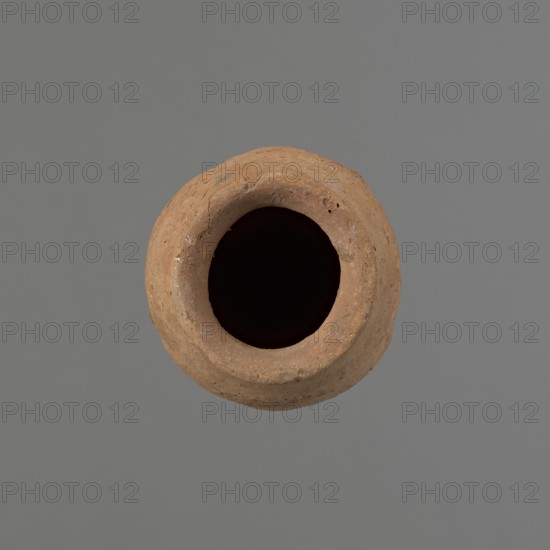Vessel with hieratic inscription, Egyptian pottery, clay vessel, conical vessel tapering toward the bottom, irregular, widest approx. 3/4 of the height; narrow, strongly sloping shoulders; short, wide neck; very gently rounded, flaring rim; pointed bottom. Handcrafted; upper part shoulders, neck, rim turned. Smooth surface, exterior probably covered with a layer of engobe. Made of Nile clay Vienna System. In the lower part of the belly there are remains of a hieratic inscription in black. The vessel is complete. Comparative material cited; dated to the Old Kingdom, ca. 2686–2181 BC, findspot Edfu. Dimensions: height 13.8 cm; rim diameter 5.7 cm; body diameter 7.5 cm., A top-down view of a round, hollow clay vessel with a rough, textured surface in shades of brown and tan, set against a flat gray background; the vessel's interior appears very dark, almost black, and the rim shows small imperfections and subtle variations in brown tones.