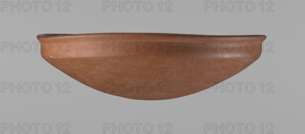 Medum-type bowl. Medum-type bowl with characteristic carination under the rim. Rounded bottom. Straight rim, slightly flaring. Narrow, very sloping shoulders — almost vertical. Diameter of the rim is larger than the diameter of the shoulders. Clay probably NB. Surface leveled and covered with a layer of engobe, then polished. Vessel color: red. Vessel complete, very well preserved. Old Kingdom late Old Kingdom, c. 2686–2181 BC. Edfu place of origin. Vessel height 7.5 cm; diameter 25.8 cm rim; diameter 25.2 cm shoulders. Comparative reference: Junker, Giza I, pl. I,2,16., A shallow rounded vessel with a smooth rim and curved body in terracotta tones of reddish-brown and orange, showing surface irregularities and fine scratch marks, with small darker speckles and subtle lighter areas, photographed against a plain light gray background.