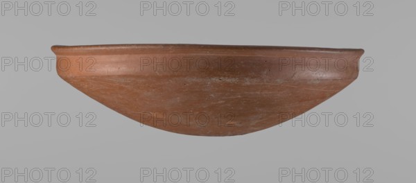 Medum-type bowl, Egyptian ceramics, Medum-type bowl with characteristic carination under the rim. Rounded bottom. Straight rim, slightly flaring. Narrow, very sloping shoulders—almost vertical. The diameter of the rim is larger than the diameter of the shoulders of the vessel. Clay probably NB. The surface of the vessel is leveled and covered with a layer of engobe, then polished. Vessel color: red. Vessel complete, very well preserved. Comparative material: Junker, Giza I, pl. I,2,16, c. 2686–c. 2181 BC; Old Kingdom late Old Kingdom. Provenance: Edfu. Vessel height 7.5 cm; diameter rim 25.8 cm; diameter shoulders 25.2 cm., A shallow, rounded bowl with a wide rim is shown against a plain gray background; the bowl has an overall reddish-brown terracotta color with areas of lighter brown and faint grayish-white discoloration, a slightly rough surface texture with visible scuffs and small pits, a gently curved profile tapering to a rounded base, and the rim appears slightly thicker and sm...