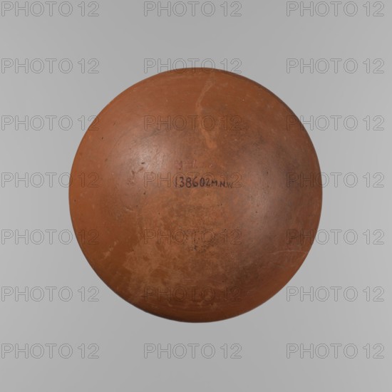 Medum-type bowl, Medum-type bowl with characteristic carination under the rim. Rounded bottom. Straight, slightly flaring rim. Narrow, sloping shoulders. The diameter of the rim is smaller than the diameter of the vessel's shoulders. Surface leveled and covered with a layer of engobe, then polished. Vessel color: red. Vessel cracked and glued together; minor clay losses on the rim filled with plaster. Old Kingdom 6th Dynasty?, ca. 2686–2181 BC; Edfu place of origin. Vessel; height 8.9 cm; diameter 21.7 cm rim; diameter 22.3 cm shoulders., A round, single object fills most of the image, appearing as a worn spherical form in shades of brown, reddish-brown, and tan with areas of darker brown mottling and lighter tan scuffs; the surface shows a slightly rough, matte texture with small speckles and faint scratches, and a visible seam or crack near the top. The background is a smooth, neutral gray gradient.