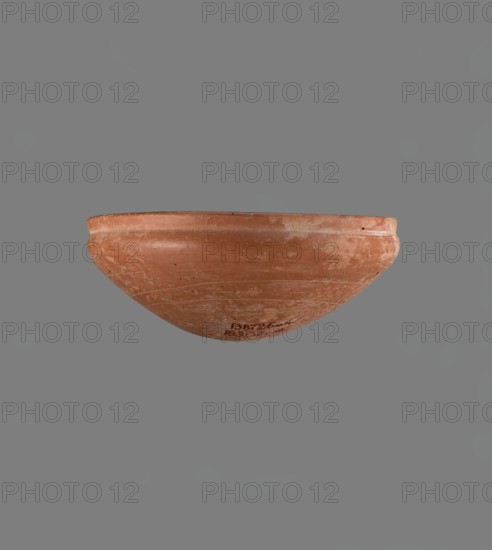 Medum type bowl, Medum type bowl with characteristic carination under the rim. Rounded bottom. Straight rim, slightly flaring. Narrow, sloping shoulders. The diameter of the rim is smaller than the diameter of the vessel's shoulders. Clay probably NB1. The surface is leveled and covered with a layer of engobe, then polished. Vessel colour: red. Complete, very well preserved. c. 2686–c. 2181 BC; Old Kingdom, Edfu. Vessel; height 4.2 cm; diameter 21.1 cm rim and shoulders., A shallow rounded bowl viewed from the side, made of terracotta with a worn, matte surface showing scratches and scuffs; the rim is slightly raised and the body tapers to a rounded base. The bowl is primarily reddish-brown with areas of lighter, dusty tan wear and a few darker spots. The background is a flat gray.