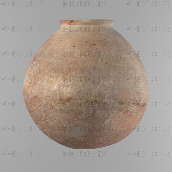 Vessel, Vessel with an almost spherical belly, widest about 1/3 of the vessel's height. Sloping shoulders. Neck poorly defined – very short and wide. Rounded, slightly flaring rim. Rounded bottom. Made of Nile clay NB. Surface smooth; outer surface finished to about half its height with a knife or similar tool. A rather indistinct cord impression around the widest diameter of the belly. Colour light red. Chipped rim and traces of salting in places over the entire surface. Comparative typology: similar to types II–III Old Kingdom, ca. 2686–2181 BC, provenance Edfu. Dimensions: height 24.9 cm; rim diameter 10.3 cm; body diameter 24.2 cm., A large round clay vessel with a narrow neck and a slightly flared rim, shown against a plain gray background; the vessel has a rough, weathered surface with visible pitting and texture, and an overall color palette of earthy browns and muted reds with patches of pale beige and hints of gray and rusty orange.