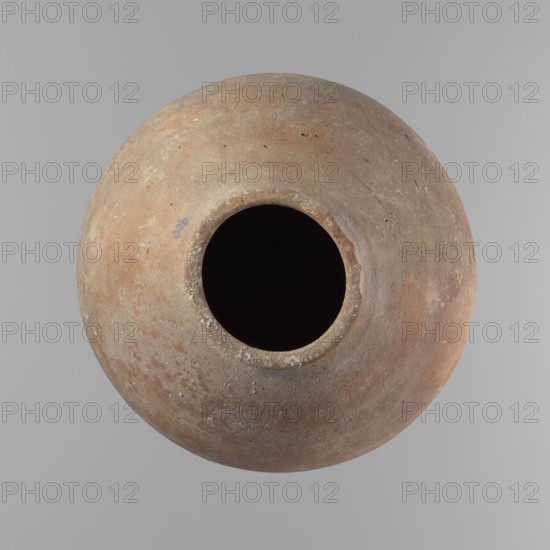Vessel, Egyptian clay vessel with an almost spherical belly, widest about 1/3 of the vessel's height; sloping shoulders; poorly defined, very short and wide neck; rounded, slightly flaring rim; rounded bottom. Made of Nile clay NB. Surface smooth; outer surface finished to about half its height with a knife or similar tool; rather indistinct cord impression around the widest diameter of the belly. Light red color. Chipped rim and traces of salting across the surface. Comparative typology: type II–III, Old Kingdom ca. 2686–2181 BC. Dimensions: height 24.9 cm; rim diameter 10.3 cm; body diameter 24.2 cm. Origin: Edfu., A round clay vessel viewed from above with a central circular opening showing a dark interior, the vessel surface displaying a weathered texture and a mix of earthy colors including brown, tan, beige, and hints of gray, with some lighter speckles and small rough patches on the rim and body.