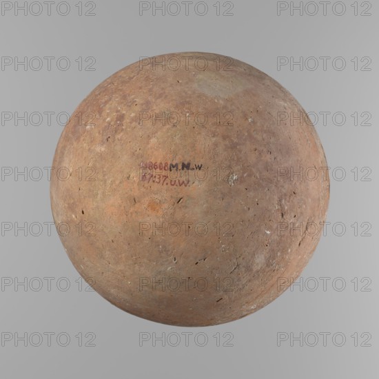 Vessel, Egyptian ceramic vessel with an almost spherical belly, widest about 1/3 of the vessel's height; sloping shoulders; poorly defined, very short and wide neck; rounded, slightly flaring rim; rounded bottom. Made of Nile clay; surface smooth. Outer surface finished to about half its height with a knife or similar tool; a rather indistinct cord impression around the widest diameter of the belly. Colour light red. The vessel has a chipped rim and traces of salting in places over the entire surface. Comparative typology: similar to Mycerinus-period types II–III, ca. 2686–2181 BC Old Kingdom, Edfu. Dimensions: height 24.9 cm; rim diameter 10.3 cm; body diameter 24.2 cm., A spherical, weathered object with a rough, pitted surface in shades of brown, tan, ochre, and muted orange sits centered against a smooth light gray background; the surface shows patches of lighter and darker brown, small irregular holes and abrasions, and a few areas of off-white and pale greenish discoloration, wit...