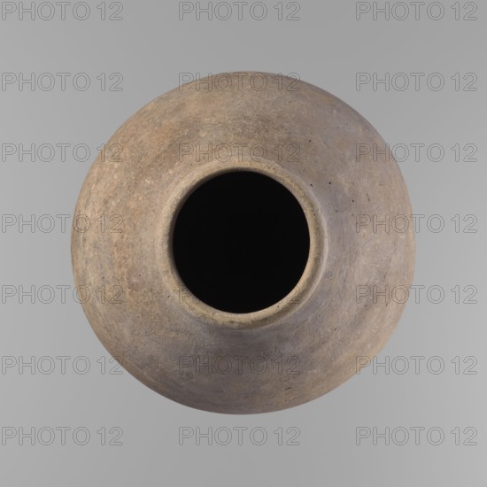Vessel, Ceramics; Egyptian clay vessel with ovoid belly, widest about halfway up. Wide, short, almost cylindrical neck; rounded, slightly tapering rim; rounded bottom. Made of Nile clay in two parts joined about one-third of the vessel's height. Even surface; beige color; complete. Comparative dating: ca. 2686–2181 BC, Old Kingdom, Edfu. Dimensions: height 35.5 cm; rim diameter 10.2 cm; body diameter 22.2 cm. References to typology: Reisner, type V–XI,7 and XV–XVI., A round clay vessel viewed from above with a dark central opening, the vessel showing a textured surface in shades of brown, tan, gray, and muted ochre with slight variations and speckling, set against a smooth light gray background.