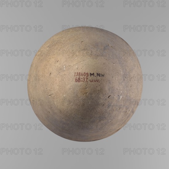 Vessel with an ovoid belly, widest about halfway up. Wide, short, almost cylindrical neck. Rounded, slightly tapering rim. Rounded bottom. Made of Nile clay in two parts, joined about 1/3 of the vessel's height. Surface even; beige color; complete. Ceramic Egyptian vessel, clay. Comparative typology: type V-XI,7 and XV-XVI; ca. 2686–2181 BC Old Kingdom, Edfu. Dimensions: height 35.5 cm; rim diameter 10.2 cm; body diameter 22.2 cm., A round, weathered object with a rough, pitted surface in shades of beige, tan, light brown, gray, and muted purple, centered against a smooth light gray background; the object shows irregular small marks and scuffs and a few darker specks across its surface, with a small area near the center that appears slightly smoother and a few subtle variations in color tone around its curvature.