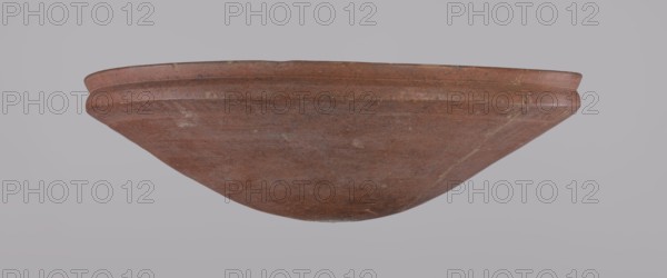 Medum-type bowl with characteristic carination under the rim. Rounded bottom. Straight, slightly flaring rim. Narrow, sloping shoulders; the diameter of the rim equals the diameter of the shoulders. Clay probably NB1. Surface leveled, covered with an engobe layer, then polished. Vessel color red. Reassembled from original fragments; minor losses on the rim. Circa 2686–2181 BC Old Kingdom, from Edfu. Vessel; height 6.9 cm, rim diameter 24.5 cm, shoulder diameter 24.9 cm., A wide shallow bowl with a rounded base shown upside down, displaying a smooth rim and a gently curved exterior surface; the object is predominantly reddish-brown with variations of darker and lighter brown patches and a few pale spots and streaks, set against a pale gray background.