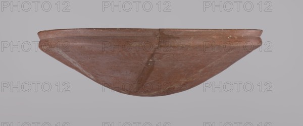 Medum-type bowl, Egyptian pottery, Medum-type bowl with characteristic carination under the rim. Rounded bottom. Straight, slightly flaring rim. Narrow, sloping shoulders. The diameter of the rim equals the diameter of the vessel's shoulders. Clay probably NB1. The surface was leveled, covered with an engobe, and polished. Vessel color: red. Vessel glued together from original fragments; minor losses on the rim. c. 2686–c. 2181 BC Old Kingdom, from Edfu. Vessel; height 6.9 cm; diameter 24.5 cm rim, 24.9 cm shoulders., A shallow rounded vessel viewed from the side with a curved rim and a smooth interior surface, showing a visible crack and some surface wear; the object is primarily reddish-brown with lighter beige and pale brown streaks and spots, set against a pale gray background.