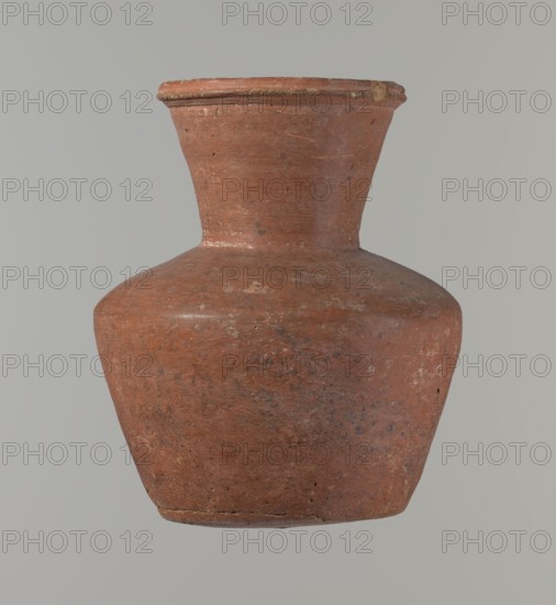 Vessel, Medium-sized clay jug with a biconical body, widest at about half its height. Wide shoulders, nearly cylindrical neck that widens toward the spout; neck height about one-third of total. Profiled, irregular spout slightly raised and extended on one side forming a small spout; spout nearly triangular in cross-section with an approx. 1 mm cylindrical bulge on the outer profile. Bottom almost flat with slight rounding. Made of Nile clay NB1? per Vienna System. Neck possibly made separately and attached to shoulders. Outer surface smoothed, covered with engobe and polished; inner surface smoothed, neck also with engobe and polished. Reddish-brown color. Quite well preserved; rim slightly chipped in two places and outer engobe worn in spots. Dated c. 2345–c. 2181 BC, Old Kingdom, 6th Dynasty, from Edfu. Vessel; height 17 cm, rim diameter 9.8 cm, body diameter 14.6 cm, bottom diameter 9.5 cm. Comparable forms: Saqqara II cat. 210–211, form 35., A single clay vessel with a wide rounded...