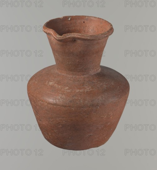 Vessel, Egyptian ceramics, clay vessel, jug. Medium-sized jug with a biconical body, widest at about half its height. Wide shoulders, not very sloping. Wide, almost cylindrical neck widening towards the spout; neck height about one-third of total vessel height. Profiled, irregular spout, slightly raised and extended on one side forming a small spout. Spout nearly triangular in cross-section, with an approximately millimeter-sized cylindrical bulge at center of outer profile. Bottom almost flat with very slight rounding. Made of Nile clay NB1? — Vienna System. Neck possibly made separately and attached to the shoulders. Outer surface smoothed, covered with an engobe and polished. Inner surface smoothed, except for the neck which is also engobed and polished. Color reddish-brown. Fairly well preserved; rim slightly chipped in two places and outer engobe worn in places. Comparative material: Rzeuska, Saqqara II, cat.210–211 form 35; Louvre E 16586. Date: c. 2345–c. 2181 BC; Old Kingdom, 6...