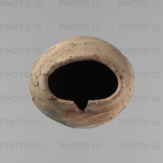 Vessel, Egyptian pottery, hand-made clay vessel with a conical belly, widest in its upper part approximately 4/5 of the vessel's height. Rounded bottom. Irregularly marked shoulders—clearly sloping on one side, short and almost horizontal on the opposite. Straight, slightly tapering rim. Made of Nile clay with numerous organic inclusions and limestone particles visible on the surface. Uneven surface with numerous depressions; carelessly made. Brown color. Cracks on the surface resulting from poor clay kneading. Ca. 2686–ca. 2181 BC Old Kingdom, Edfu. Vessel. Height 38 cm; diameter rim 11.7 cm; diameter body 15.7 cm., A roughly circular, hollow clay vessel viewed from above with a large irregular opening; the exterior surface shows a textured, weathered appearance with muted beige, tan, and light brown tones along with some subtle reddish-brown areas, and the interior appears very dark to black, set against a smooth light gray background.