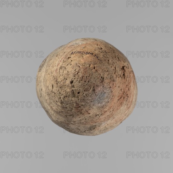 Vessel, Egyptian pottery; Vessel with a conical belly, widest in its upper part approx. 4/5 of the vessel's height. Rounded bottom. Irregularly marked shoulders—clearly sloping on one side, short and almost horizontal on the opposite. Straight, slightly tapering rim. Hand-made vessel of not very well-worked Nile clay with numerous organic inclusions and limestone particles visible on the surface. Surface uneven with numerous uneven depressions; color brown. Quite well preserved—cracks on the surface result from poor clay kneading. ca. 2686–ca. 2181 BC Old Kingdom, Edfu; vessel; height 38 cm; diameter 11.7 cm rim, 15.7 cm body., A roughly spherical, textured object with an uneven, pitted surface in shades of tan, beige, brown, and muted orange, with small patches of gray and faint bluish tones; the object sits against a uniform light gray background.