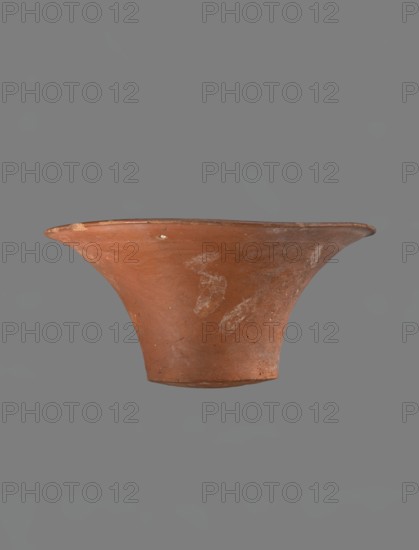 Bowl, Egyptian pottery, clay vessel — deep, cup-shaped bowl with a slightly convex bottom and sides arching upwards; straight rim, flat on top, flaring. Made of Nile clay NB1, according to the Vienna System. Covered with a layer of engobe with added red ochre and thoroughly polished. Vessel color: red. Well-preserved, with slight damage to the clay on the rim. Comparative parallels cited with early dynastic and Old Kingdom examples including IV–VI dynasties and late VI dynasty contexts. Likely Old Kingdom date ca. 2686–2181 BC. Place of origin: Edfu. Dimensions: height 13.8 cm; rim diameter 28.8 cm; bottom diameter 11.9 cm., A terracotta vessel with a flared rim and narrow base is shown against a plain gray background; the vessel is reddish-brown with patches of lighter discoloration and surface wear, small darker spots, and subtle texture variations on its curved sides.