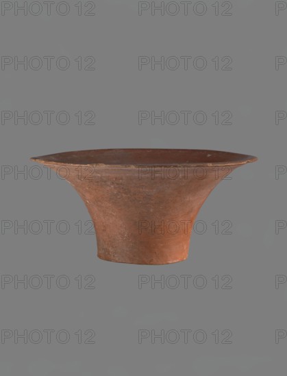 Bowl, Deep, cup-shaped clay bowl with a slightly convex bottom and sides arching upwards; straight, flat-top, flaring rim. Made of Nile clay NB1 ?. Covered with an engobe mixed with red ochre and thoroughly polished; vessel color red. Well-preserved with slight damage to the rim. Height 13.8 cm; rim diameter 28.8 cm; bottom diameter 11.9 cm. Comparable parallels attributed to Dyns. IV–VI and late VI Old Kingdom, ca. 2686–2181 BC., A single shallow vessel with a wide flaring rim and a narrower base, shown against a plain gray background; the vessel has an earthy reddish-brown color with patches of darker and lighter brown and some subtle surface texture and wear.