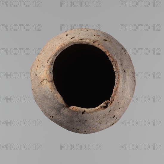 Vessel, Egyptian pottery, ceramics, clay hand-made vessel, Old Kingdom, c. 2686–c. 2181 BC; Edfu place of origin, vessel, height 33.5 cm, diameter 10.4 cm rim, diameter 15.1 cm body., A roughly circular, weathered clay vessel viewed from above with a large dark hollow center, showing a textured rim with chips and pits; the vessel surface displays shades of brown, tan, gray, and hints of reddish-orange against a flat light gray background.