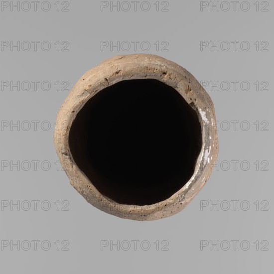 Vessel, Egyptian pottery, hand-made clay vessel, almost cylindrical, widest just below a straight tapering rim; rounded base; slightly marked, narrow sloping shoulders. Handmade from Nile clay with organic inclusions and limestone particles; surface uneven, better worked in upper part, with numerous uneven depressions and cracks from careless kneading and firing. Brown color. Fairly well preserved. Old Kingdom, ca. 2686–2181 BC; Edfu; vessel; height 36.5 cm; rim diameter 11.5 cm; body diameter 13.2 cm., A top-down view of a round, hollow clay vessel with an irregular rim, showing a rough textured exterior in shades of brown and tan, a deep black interior, and small areas of white residue on the inner rim, set against a flat light gray background.