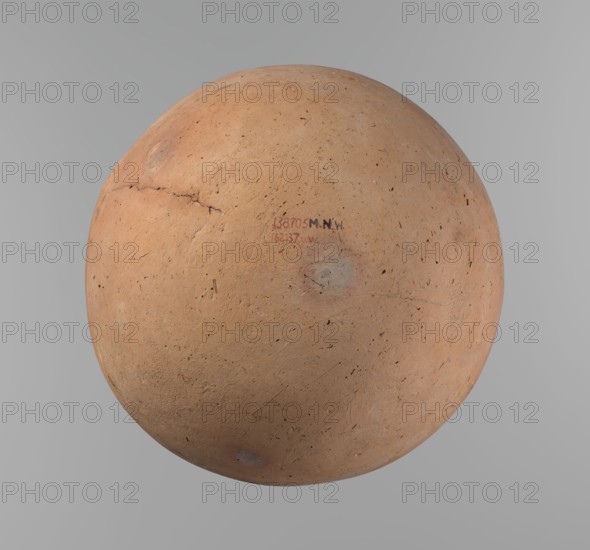 Vessel, Egyptian pottery, ceramic clay vessel. A vessel with an almost spherical, slightly horizontally stretched shape, widest about half the height. Broad, sloping shoulders, very short neck. Rounded rim, oval in cross-section, slightly flaring. Rounded bottom. Horizontal cord impressions at the widest point of the vessel. NB2 clay Vienna System with a significant amount of organic admixture. Surface smooth. Made on a wheel; approximately half of its height was worked with a knife or similar tool. Colour beige. Very well preserved. Circa 2686–2181 BC Old Kingdom, Edfu. Height 28.5 cm; rim diameter 10.4 cm; body diameter 30.410 cm., A spherical object with a rough, uneven surface in shades of terracotta and light brown, showing darker brown speckles and small pits across its face, with a visible crack running along one side and a few circular grayish patches; the background is a smooth, neutral gray.