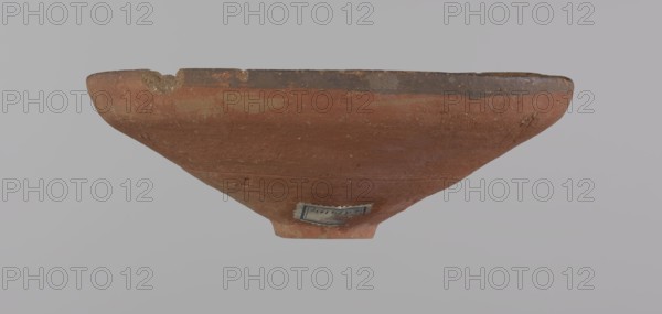 Bowl, Egyptian painted pottery bowl with conical shape and ring-shaped foot. Straight rim, slightly flaring outward, irregular. Wheel-made of Nile clay type ND Vienna System. Surface even, covered with glaze before firing; inner and outer rim bear a narrow ˜0.5 cm black band; remainder of vessel is red. Traces of polish; glaze slightly worn in places, possibly from use. Good condition with minor clay chips on rim and abrasions over surface. Analogies: Egypt's Golden Age no. 51, p. 78, ca. 1550–ca. 1425 BC; New Kingdom, early 18th Dynasty. Provenance notes: Edfu, Deir el-Medina . Vessel. Height 5.3 cm; rim diameter 15.1 cm; bottom diameter 3.1 cm., A shallow, wide bowl viewed from the side showing its rounded exterior and narrow base, with a rough, weathered surface and a chipped rim; the bowl is primarily reddish-brown with darker brown along the rim and a few lighter tan patches, set against a pale gray background.