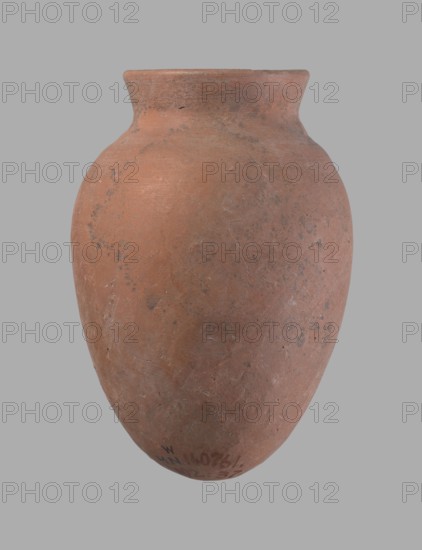 Vessel, Egyptian pottery vessel of clay, c. 2686–c. 2181 BC Old Kingdom?, from Edfu; height 16.5 cm, rim diameter 7.6 cm, belly diameter 11.2 cm., A rounded, slightly elongated clay vessel with a narrow flared rim, showing a rough matte surface and an overall terracotta color with patches of darker brown and muted gray. The form displays subtle surface irregularities and small pitted marks, with areas of lighter pinkish-orange where the clay appears smoother. The background is a uniform neutral gray.