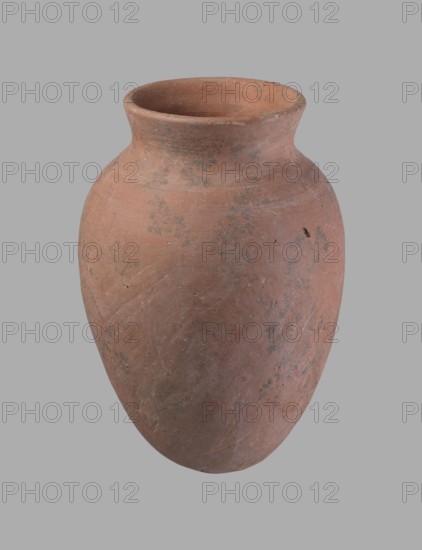 Vessel, Egyptian pottery vessel of clay, c. 2686–c. 2181 BC Old Kingdom?, from Edfu; height 16.5 cm, rim diameter 7.6 cm, belly diameter 11.2 cm., A rounded clay vessel with a wide mouth and a flared rim, showing a rough, matte surface in shades of reddish-brown with patches of darker brown and gray, small scuffs and abrasions, and subtle variations in texture across its curved body against a plain light gray background.