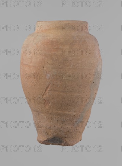 Vessel, Beer jug of a slightly irregular, conical shape with a wide, very short neck and a flat bottom. Flat, narrow shoulders and a gently rounded, straight rim. Wheel-made of Nile clay type NB2 Vienna System. Bottom is cut off with string and bears clear potter's fingerprints, flaring slightly in its lowest part. Surface even; color red. Complete and fairly well preserved, with minor damage to the bottom. New Kingdom, ca. 1550–1069 BC; Edfu. Dimensions: height 24 cm; rim dia. 10 cm; body dia. 16 cm; bottom dia. 9.2 cm., A large rounded clay vessel with a narrow flattened rim and a tapered base, showing an uneven textured surface with small pits and abrasions; the vessel displays a range of earthy colors including terracotta, light brown, pale orange, and hints of gray, with subtle horizontal striations and a few rough patches and marks.