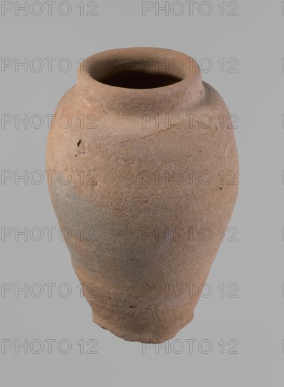 Vessel, Beer jug of a slightly irregular, conical shape with a wide, very short neck and a flat bottom. Flat, narrow shoulders and a gently rounded, straight rim. Wheel-made of Nile clay type NB2 Vienna System. The bottom is cut off with string and bears clear potter's fingerprints, flaring slightly at its lowest part. Surface even; color red. The vessel is complete and fairly well preserved, with minor damage to the bottom. New Kingdom, ca. 1550–1069 BC. Dimensions: height 24 cm; rim diameter 10 cm; body diameter 16 cm; bottom diameter 9.2 cm., A large, rounded clay vessel with a narrow, slightly flared rim and a rough, textured surface in shades of tan, light brown, and muted gray, showing small pits and irregularities and a few darker specks, photographed against a smooth light gray background.