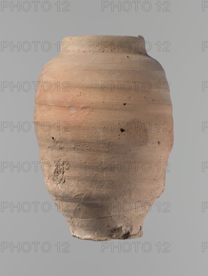 Vessel, Beer jug of a slightly irregular, conical shape with a wide, very short neck and a flat bottom. Flat, straight rim. Wheel-made from Nile clay of type NB2-ND Vienna System. Bottom cut off with string; clear potter's fingerprints around the bottom. Surface even. Clay color red. Vessel complete, fairly well preserved, with minor damage to the rim and small chips on the surface. ca. 1550–1069 BC; New Kingdom, Edfu. Vessel. Height 24.4 cm; rim diameter 9.8 cm; body diameter 16.3 cm; bottom diameter 8.5 cm., A rounded, slightly irregular clay vessel with a narrow base and a wider shoulder is shown against a plain background; the vessel has a rough, textured surface with visible tool marks, small pits, and areas of surface abrasion, and its color palette includes shades of terracotta, light brown, pale beige, and hints of gray.