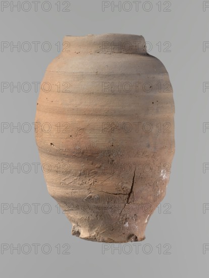 Vessel, Beer jug of a slightly irregular, conical shape with a wide, very short neck and a flat bottom. Flat, straight rim. Wheel-made from Nile clay of type NB2-ND Vienna System. Bottom is cut off with string, with clear potter's fingerprints around the bottom. Surface even. Clay color: red. Vessel complete, fairly well preserved, with minor damage to the rim and small chips on the surface. ca. 1550–ca. 1069 BC; New Kingdom, Edfu. Vessel. Height 24.4 cm; rim diameter 9.8 cm; body diameter 16.3 cm; bottom diameter 8.5 cm., A weathered clay vessel with an uneven rounded body and a narrow rim, showing a rough, textured surface with visible horizontal turning marks and small pits; the lower part has cracks, chips, and areas of abrasion, and there are traces of whitish deposits in places. The visible colors are various shades of tan, brown, reddish-brown, pale beige, and small hints of gray.