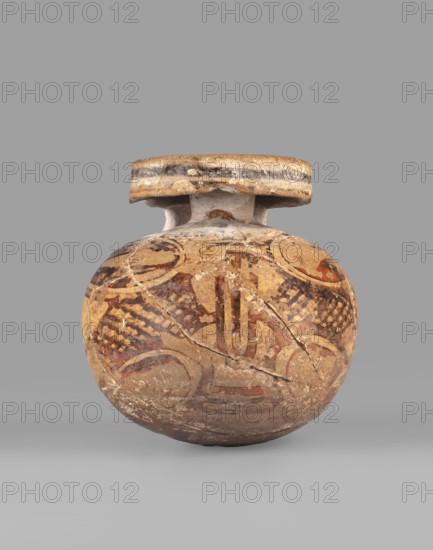 Orientalizing aryballos, Greece, Late Corinthian period. Globular aryballos with a flat rim disc and a wide ribbon-like handle. Decoration: a band and two circular lines on the top of the rim; a narrow band on the rim flare. On the front of the belly: four lotus buds interspersed with palmettes and two hatched areas. Yellowish clay. Black firnis changed to brown. Dated 580–550 BC Late Corinthian I. Corinth provenance. Vessel aryballos. Height 6.7 cm, width 6.5 cm., A round, weathered ceramic vessel with a wide, flat rim and short neck sits against a plain gray background; the vessel's surface shows an aged, cracked texture and is decorated with faded painted patterns in colors including tan, brown, reddish-brown, black, and hints of white, featuring curved and linear motifs and areas of crosshatched markings, with visible chips and worn edges around the rim and body.