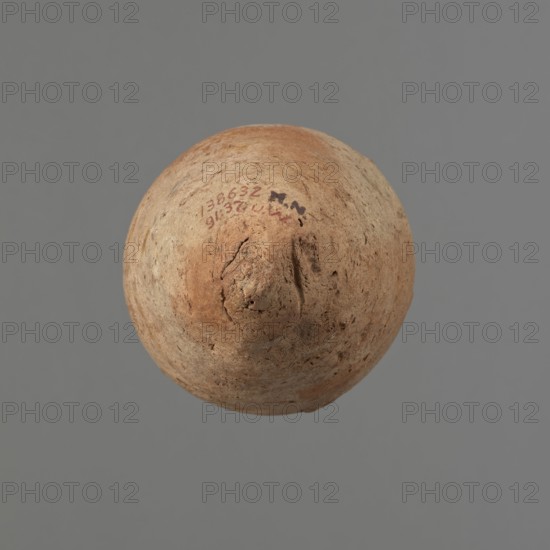 Vessel with hieratic inscription. Egyptian pottery, clay conical vessel tapering toward the bottom, slightly irregular; widest at approx. 3/4 of the height. Narrow, slightly sloping shoulders; short, wide neck; thickened, rounded, slightly flaring rim; pointed bottom. Handcrafted, upper part shoulders, neck, rim turned. Smooth surface, externally probably covered with a layer of engobe. Made of Nile clay Vienna System. Color: red exterior, beige interior. Remains of a hieratic inscription in black on the lower part of the belly. Rim slightly damaged in several places. Old Kingdom, ca. 2686–2181 BC. Height 13.8 cm; rim diameter 5.9 cm; belly diameter 8.9 cm. Analogies: Petrie, Dendera; Hope, Akhmim; Reisner, Mycerinus; Brunton, Qau and Badari; Mace, Naga ed-Der; Reisner, Naga ed-Der; Petrie, Abydos; Keiser, Avila, Dreyer, Jaritz, Laskowska-Kusztal, MDAIK 40., A roughly spherical object with an uneven, textured surface sits against a plain gray background; the object shows a range of ear...