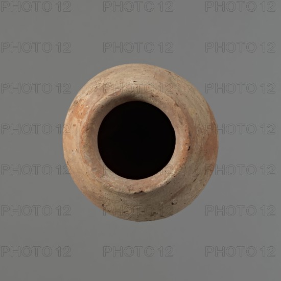 Vessel with hieratic inscription. Egyptian pottery, clay conical vessel tapering toward the bottom, irregular, widest approx. 3/4 of the height. Narrow, sloping shoulders; short, wide neck; very gently rounded, slightly flaring rim; pointed bottom. Handmade, with upper part shoulders, neck, rim turned. Surface even, outer probably covered with engobe. Made of Nile clay NB2 Vienna System. Remains of a hieratic inscription in black on lower part of the belly. Quite well preserved with minor rim damage. Analogies: examples published by Petrie, Hope, Reisner, Brunton, Mace, Keiser et al.; stylistically dated to the Old Kingdom ca. 2686–2181 BC. Findspot: Edfu. Dimensions: height 16.1 cm; rim diameter 6 cm; belly diameter 9 cm., A rounded clay vessel viewed from above with a wide dark opening, showing a textured surface in shades of tan, brown, and muted orange against a flat gray background.