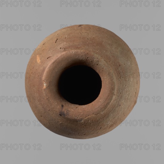 Vessel with hieratic inscription, Ceramics: Egyptian conical clay vessel Nile clay NB2, Vienna System, tapering toward a pointed bottom; irregular, widest at approx. 3/4 of the height. Narrow, slightly sloping shoulders; short, wide neck; very gently rounded, slightly flaring rim. Handcrafted with upper part shoulders, neck, rim turned; surface leveled. Remains of hieratic inscription in black on lower part of the belly. Fairly well preserved with slight damage to the rim. Old Kingdom, ca. 2686–2181 BC earlier parallels dated to 4th–5th Dynasty. Height 15.2 cm; rim diameter 5.1 cm; belly diameter 8.3 cm. Analogies: Petrie Dendera, Abydos, Hope Akhmim, Reisner Mycerinus; Naga ed-Der, Brunton Qau and Badari, Mace Naga ed-Der II, Keiser, Avila, Dreyer, Jaritz, Laskowska-Kusztal., A round, top-down view of a clay pot with a wide circular opening at its center; the pot surface appears rough and uneven with small pits and scratches, showing a range of earthy brown tones with areas of reddish...