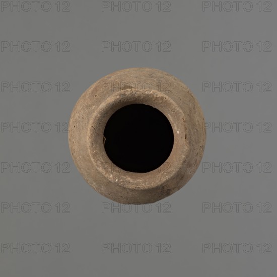 Vessel with hieratic inscription. Egyptian pottery ceramic conical vessel tapering toward the bottom, irregular, widest approx. 3/4 of the height. Narrow, sloping shoulders; short, wide neck; very gently rounded, slightly flaring rim; pointed bottom. Handmade, with upper part shoulders, neck, rim turned. Surface even, outer probably covered with a layer of engobe. Made of Nile clay NB2 Vienna System. In the widest diameter are shallow horizontal lines made before firing. Remains of a hieratic inscription in black on the lower body. Quite well preserved — slight damage on the rim. Old Kingdom, ca. 2686–2181 BC. Height 14.1 cm; rim diameter 5.6 cm; body diameter 7.8 cm. Comparable examples: Petrie Dendera, Abydos, Hope Akhmim, Reisner Mycerinus, Naga ed-Der, Brunton Qau and Badari, Mace Naga ed-Der II, Keiser et al., A round, open-mouthed clay vessel viewed from above, showing a rough textured rim and an interior that appears very dark; the vessel is a brownish-beige color with small dar...